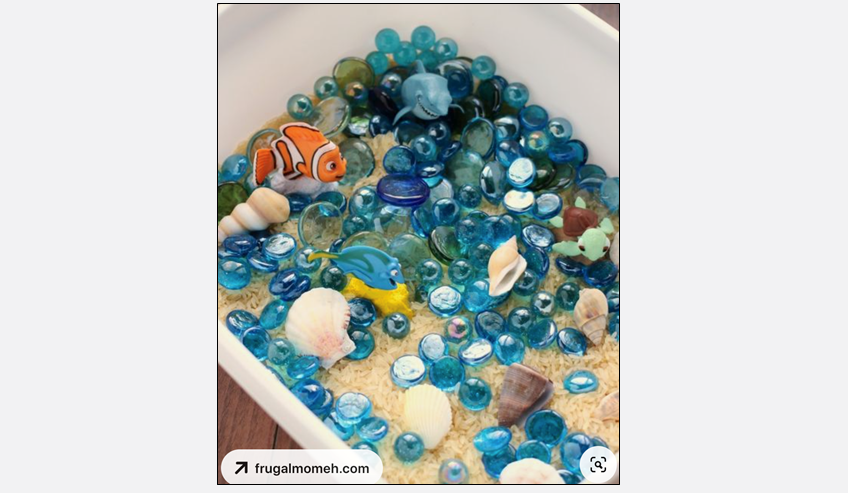 a sensory bin with sand, glass stones, and other objects