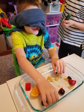blindfolded child feeling pieces of fruit